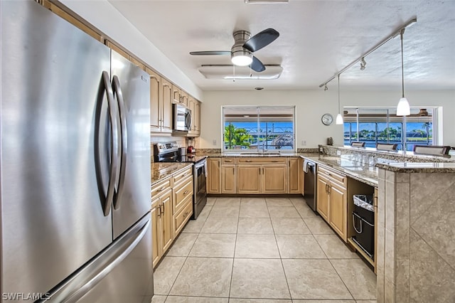 kitchen with stone counters, appliances with stainless steel finishes, and a wealth of natural light