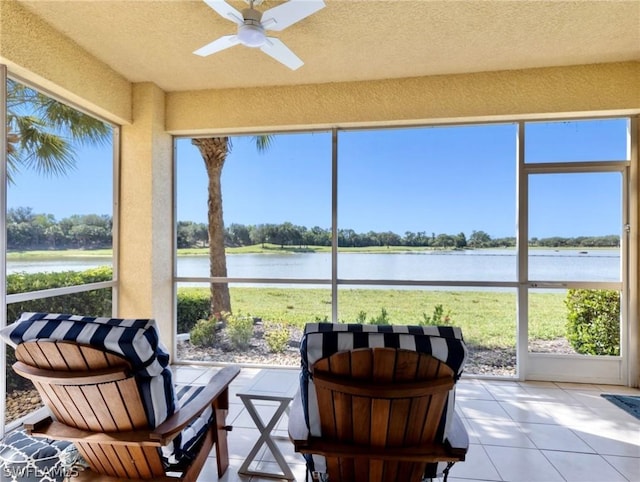 sunroom with ceiling fan and a water view