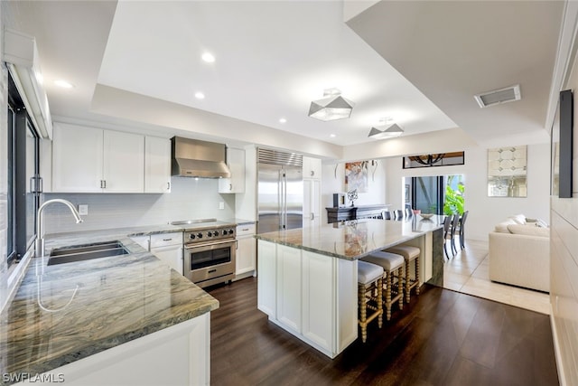 kitchen featuring sink, wall chimney exhaust hood, dark hardwood / wood-style floors, a kitchen island, and stainless steel appliances