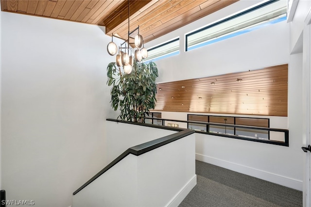 stairway featuring carpet flooring, lofted ceiling with beams, wooden ceiling, and a chandelier