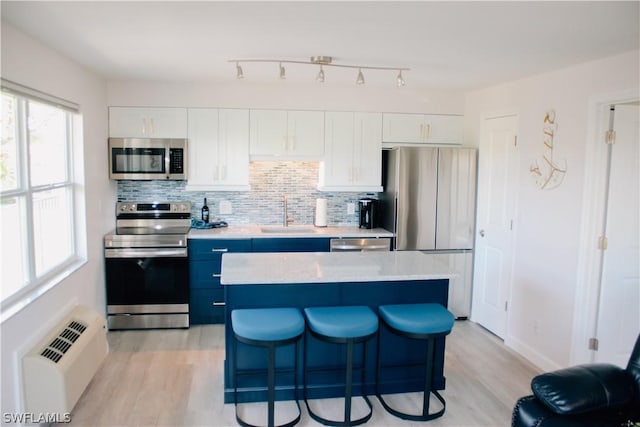 kitchen featuring sink, white cabinetry, stainless steel appliances, tasteful backsplash, and a kitchen island