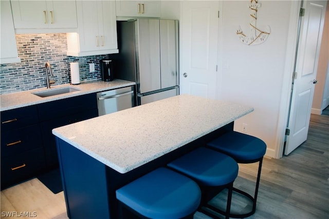 kitchen featuring sink, a kitchen island, stainless steel appliances, decorative backsplash, and white cabinets