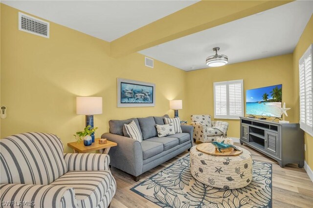 living room with beam ceiling and light hardwood / wood-style flooring