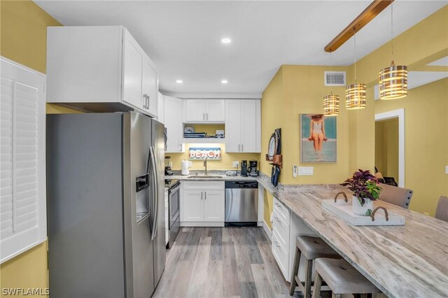 kitchen featuring sink, appliances with stainless steel finishes, hanging light fixtures, a kitchen breakfast bar, and light stone counters