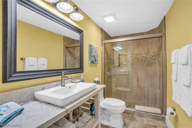 bathroom featuring sink, an enclosed shower, and toilet