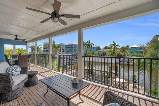 wooden deck with a water view, ceiling fan, and an outdoor living space