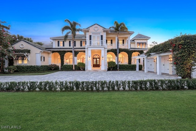 greek revival inspired property featuring a balcony and a front yard