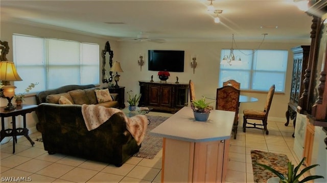 living room featuring ceiling fan with notable chandelier, light tile patterned flooring, and crown molding