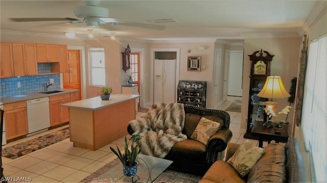 kitchen featuring decorative backsplash, white appliances, crown molding, light tile patterned floors, and a center island