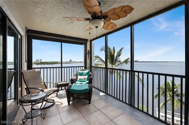 unfurnished sunroom featuring ceiling fan and a water view