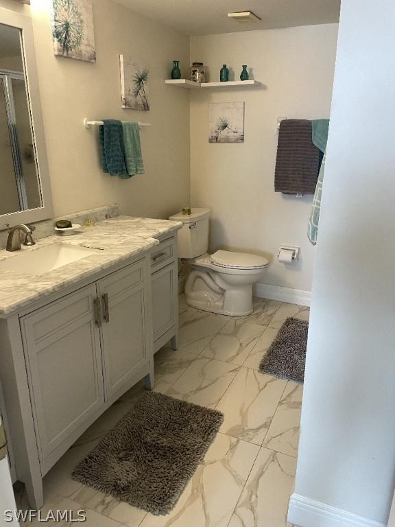 bathroom featuring vanity, toilet, and walk in shower