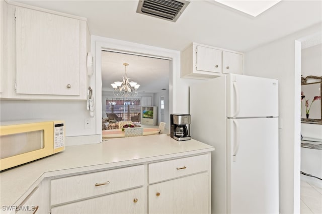 kitchen with light tile patterned floors, white appliances, and an inviting chandelier