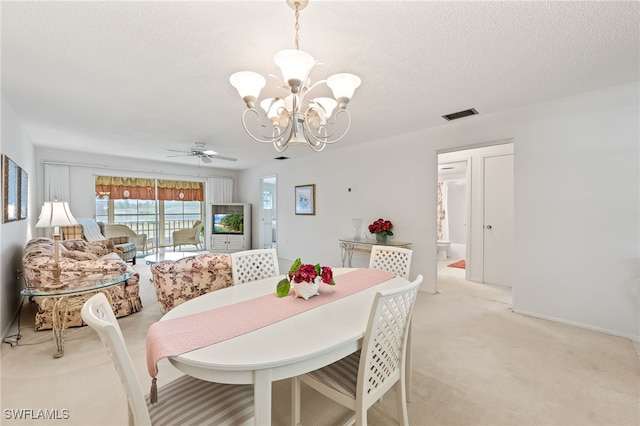 carpeted dining area featuring ceiling fan with notable chandelier and a textured ceiling