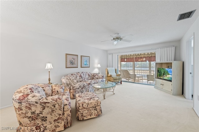 carpeted living room with a textured ceiling and ceiling fan