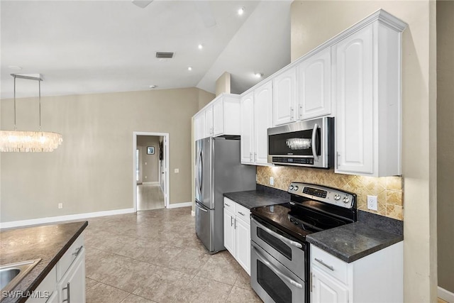 kitchen featuring lofted ceiling, white cabinetry, decorative light fixtures, appliances with stainless steel finishes, and decorative backsplash