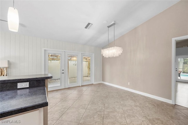 unfurnished dining area with french doors, a chandelier, vaulted ceiling, and light tile patterned floors