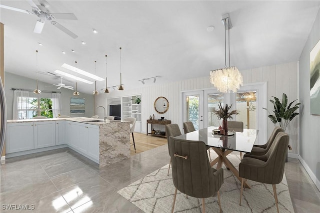 dining room featuring french doors, vaulted ceiling with skylight, ceiling fan with notable chandelier, and sink