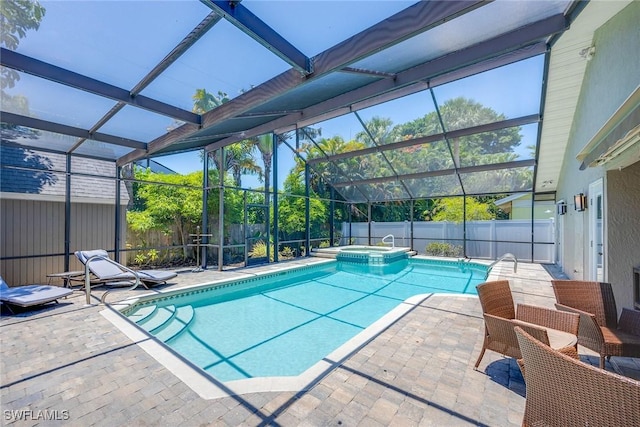 view of pool featuring a patio area, glass enclosure, and an in ground hot tub