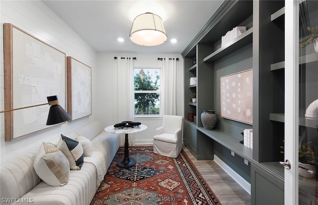 living area featuring built in shelves and hardwood / wood-style flooring