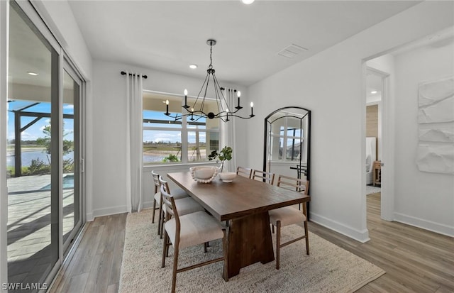 dining space with light hardwood / wood-style floors and a notable chandelier