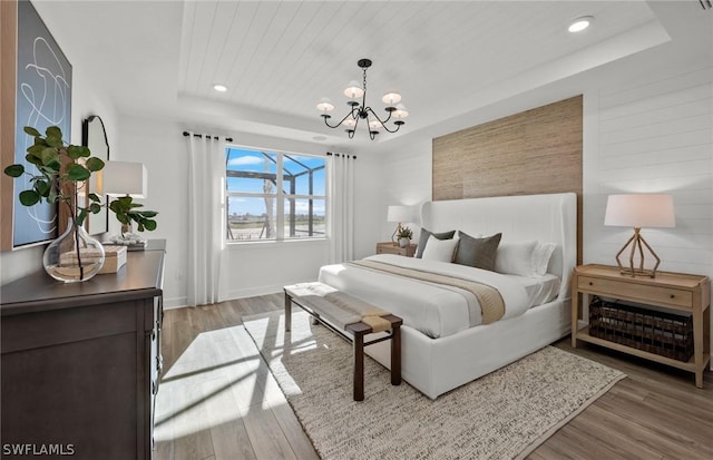 bedroom featuring wood ceiling, an inviting chandelier, a raised ceiling, and hardwood / wood-style flooring