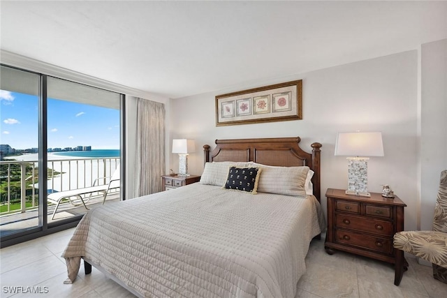 bedroom featuring access to outside, a water view, and expansive windows