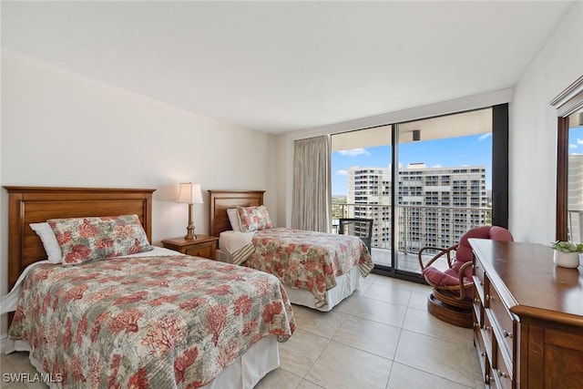 bedroom with light tile patterned floors, a view of city, a wall of windows, and access to outside