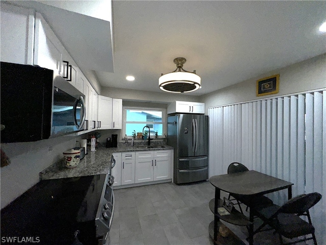 kitchen featuring white cabinets, appliances with stainless steel finishes, sink, and light stone counters