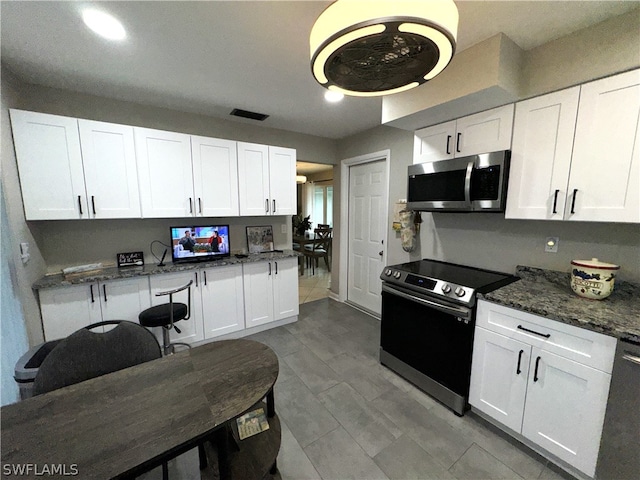 kitchen featuring stainless steel appliances, dark stone counters, and white cabinetry