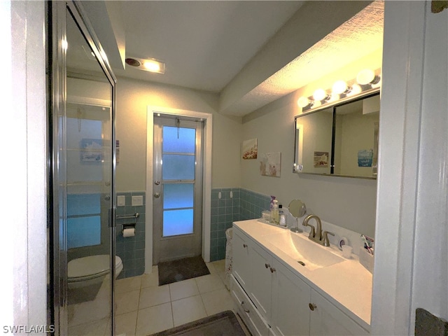 bathroom with vanity, tile walls, tile patterned flooring, and toilet