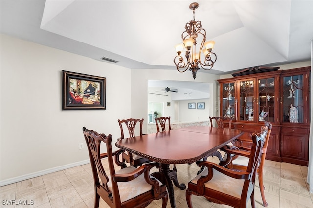 dining room with a raised ceiling and ceiling fan with notable chandelier