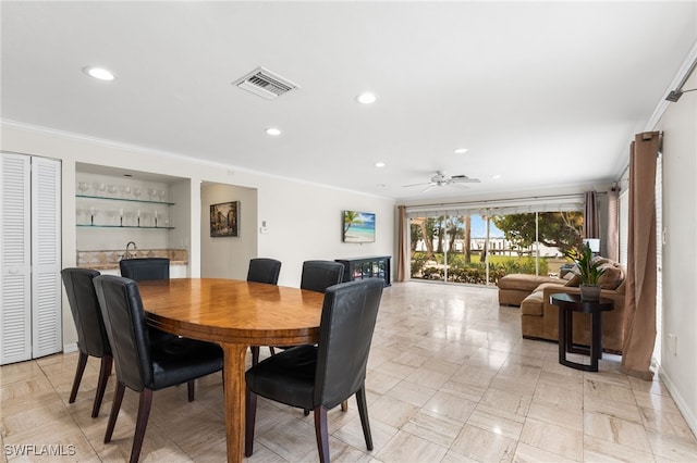 dining space featuring ornamental molding, bar, and ceiling fan