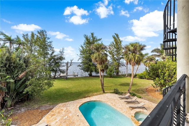 view of swimming pool featuring a water view, a yard, and a patio area