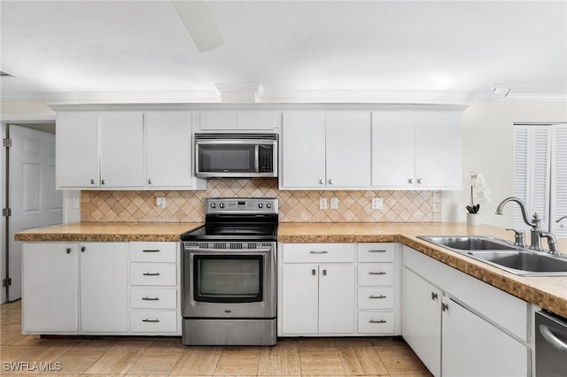 kitchen featuring appliances with stainless steel finishes, tasteful backsplash, sink, white cabinets, and crown molding