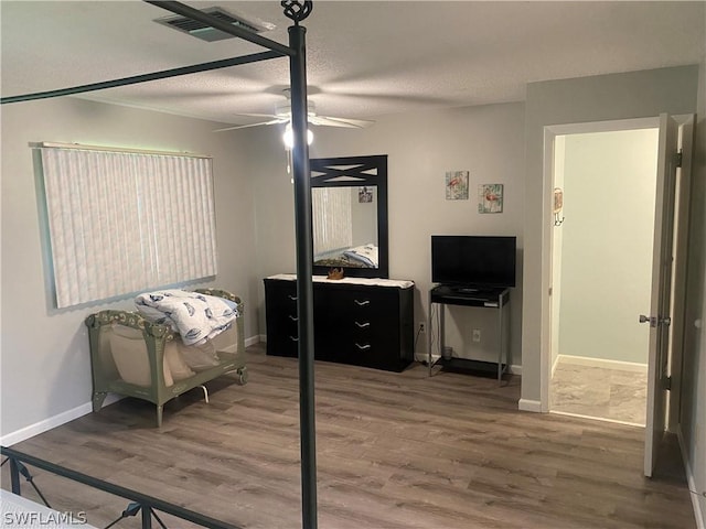 bedroom with visible vents, a ceiling fan, a textured ceiling, wood finished floors, and baseboards