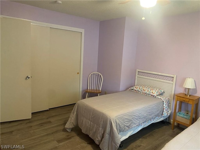 bedroom with a textured ceiling, a closet, wood finished floors, and a ceiling fan