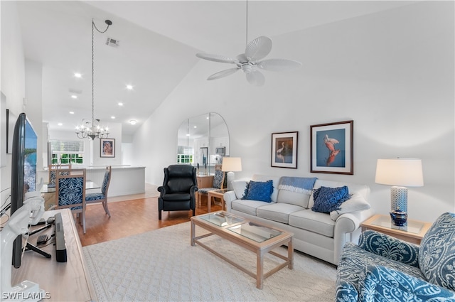 living room featuring ceiling fan with notable chandelier, light hardwood / wood-style floors, and high vaulted ceiling