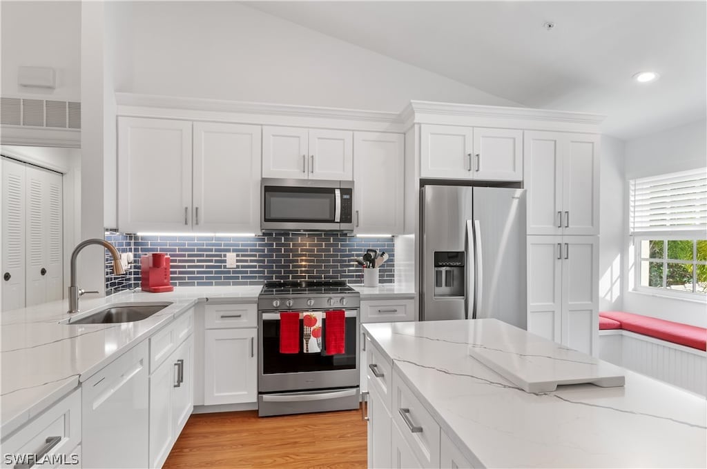 kitchen with light stone countertops, sink, white cabinets, and appliances with stainless steel finishes