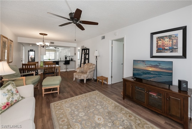 living room with a textured ceiling, ceiling fan with notable chandelier, and dark wood-type flooring