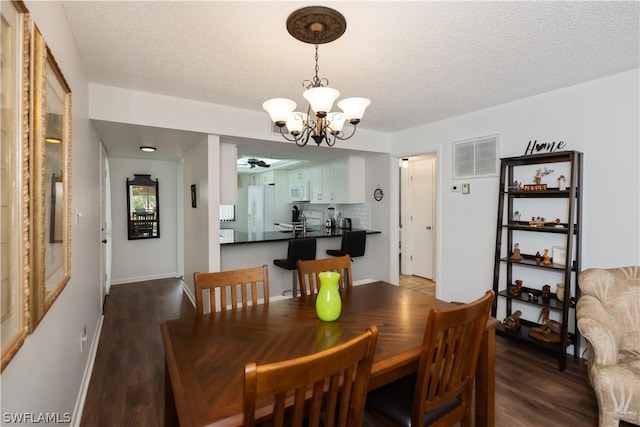 dining space with a chandelier, a textured ceiling, and dark hardwood / wood-style flooring