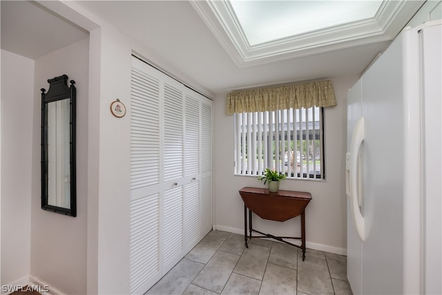 corridor featuring light tile patterned floors and crown molding