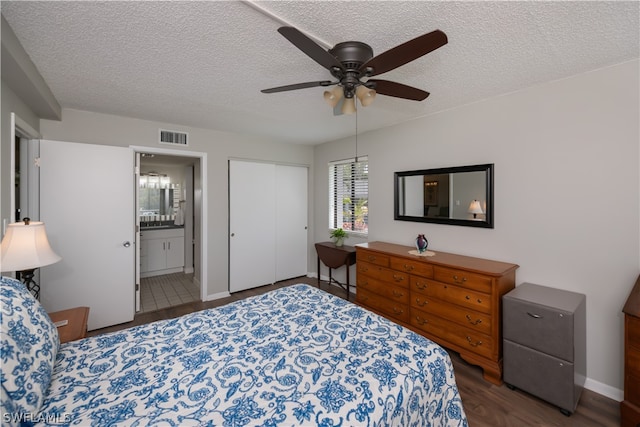 bedroom with ceiling fan, dark hardwood / wood-style flooring, ensuite bathroom, a textured ceiling, and a closet