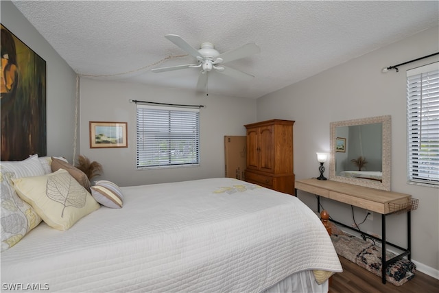 bedroom with ceiling fan, dark hardwood / wood-style flooring, and a textured ceiling