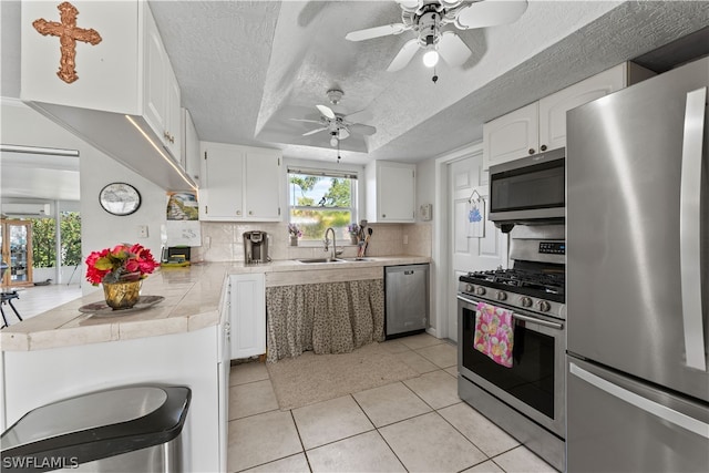 kitchen featuring white cabinetry, stainless steel appliances, backsplash, ceiling fan, and light tile floors