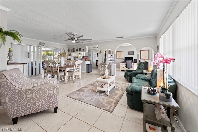 living room with crown molding, a textured ceiling, ceiling fan, and light tile floors