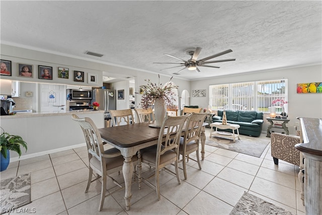 tiled dining space featuring crown molding, ceiling fan, and a textured ceiling