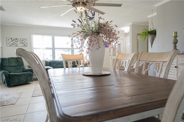 tiled dining room with ceiling fan, ornamental molding, and a textured ceiling