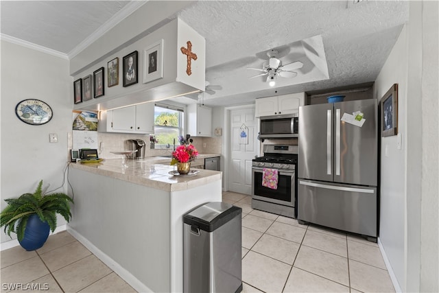 kitchen featuring ceiling fan, stainless steel appliances, a textured ceiling, backsplash, and white cabinets