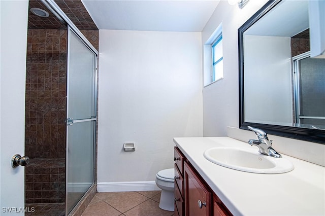 bathroom featuring toilet, vanity, tile patterned flooring, and a shower with door