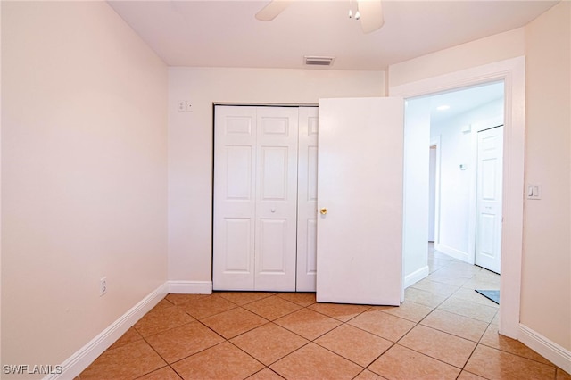 unfurnished bedroom with a closet, light tile patterned flooring, and ceiling fan